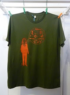 T-shirt vert et sérigraphie orange d'un homme qui parle 100x ni l'oie.