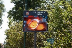 Ecran vidéo publicitaire fixé à un poteau dans une rue piétonne