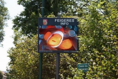 Ecran vidéo publicitaire fixé à un poteau dans une rue piétonne